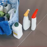 Close up view of bottles with detergent and basket indoors on the floor.