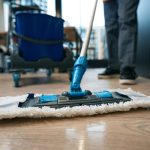 Work of cleaning company specialists in the coworking area, workers use a mop and buckets on a special cart